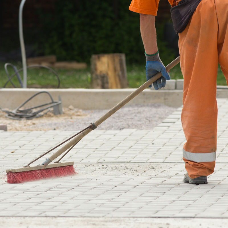guy cleaning up a construction site with a broom