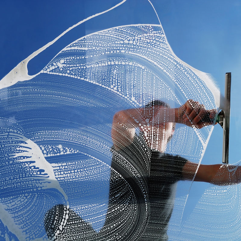 man using squeegee cleaning window